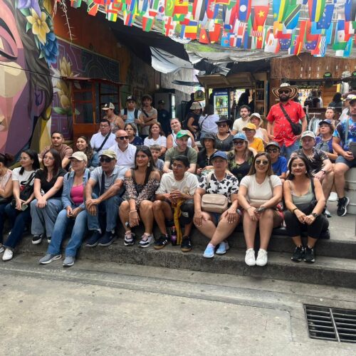 Travelers exploring colorful graffiti murals and outdoor escalators during a Private Comuna 13 Tour Medellin with a local guide.